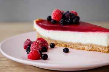 close-up of raspberries and blueberries on a cheesecake background on a pink plate on a wooden table