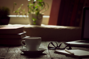 A cup of coffee in the workplace on a wooden table. A cup of coffee in the workplace on a wooden table. The concept of working outside the office