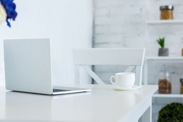 Fototapeta na wymiar laptop and cup of coffee on white table kitchen
