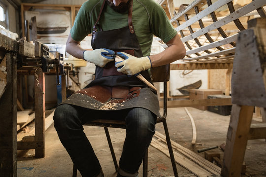 Mid section of carpenter making wooden spoon with worktool
