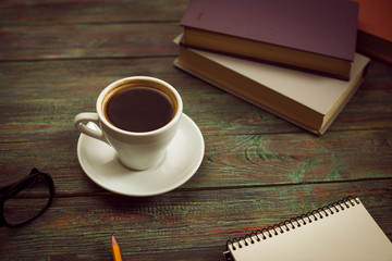 A cup of coffee in the workplace on a wooden table. A cup of coffee in the workplace on a wooden table. The concept of working outside the office