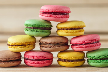 Green, pink, yellow and brown french macarons on the wooden boards