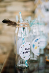 close-up of a glass bottle with an inscription birthday and a straw to which a feather is tied