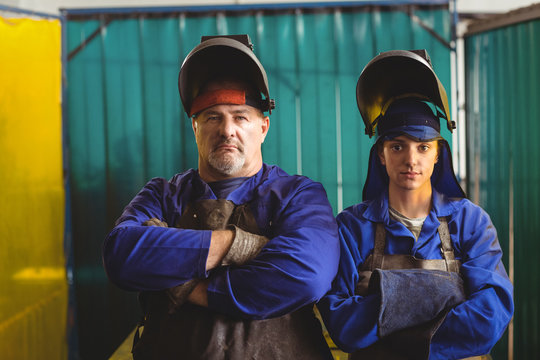 Portrait of male and female welder standing with arms crossed