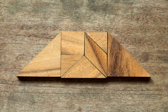 Tangram puzzle in trapezoid shape on wood background