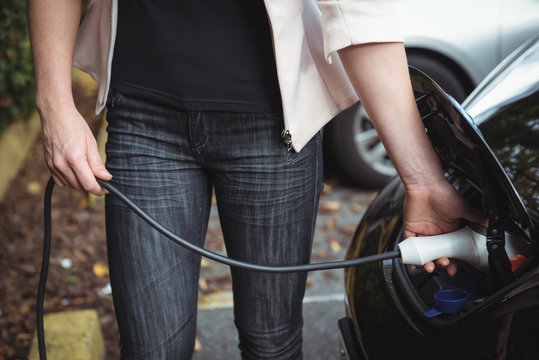 Mid section of woman charging electric car