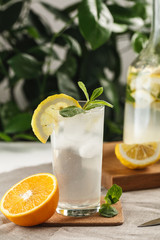 citrus mint lemonade with ice cubes in glass Cup next to vintage carafe. Summer drink Limoncello