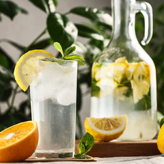 citrus mint lemonade with ice cubes in glass Cup next to vintage carafe. Summer drink Limoncello
