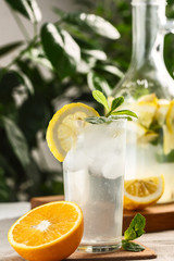 citrus mint lemonade with ice cubes in glass Cup next to vintage carafe. Summer drink Limoncello