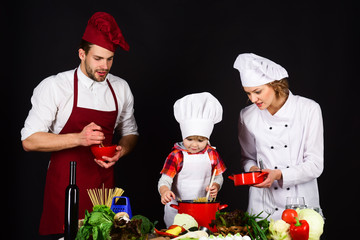 Child with parents at kitchen table cooking. Happy loving family are preparing dinner together. Homemade food. Cute little boy and his parents are smiling while cooking. Concept of friendly family.