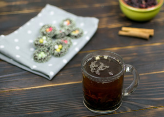 A cup with herbal tea and cookies on a dark background.