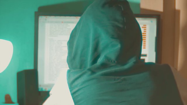 Hacker man programmer in the hood using computer for hack information and data from user account. teal orange color grading web indoors online social media