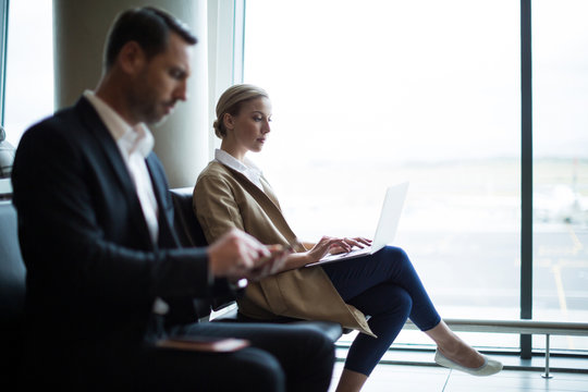 Businesspeople using mobile phone and laptop