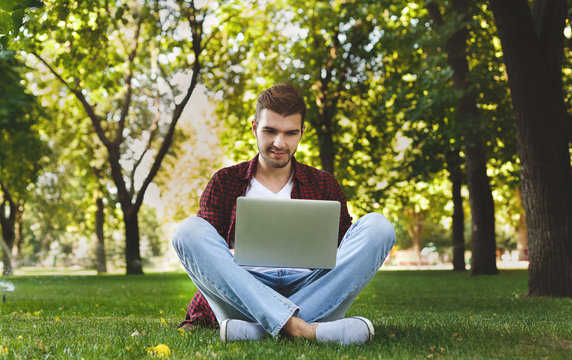 Handsome young man using a laptop outdoors