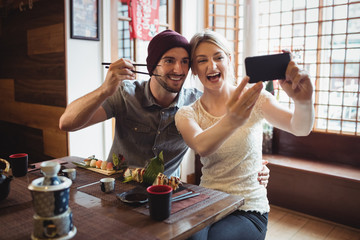 Couple taking selfie while having sushi