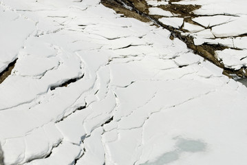 Plakat crevasse in the snow and ice, caused by high temperatures, above a frozen lake of a dam, dangerous for ski mountaineers, avalanche danger, high mountain, spring, Formazza Valley, Piedmont, Italy