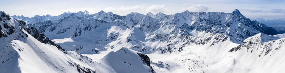 Poster Ein großes, weites Panorama einer schneebedeckten Berglandschaft. © gubernat
