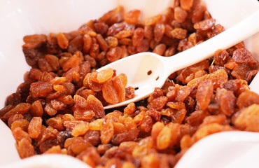 Fresh raisins and spoon in a white bowl