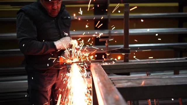 Man works with grinder cutting metal.