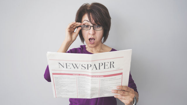 Shocked woman reading the newspaper