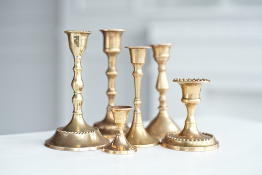 Set Of Vintage Brass Candlesticks On White Table Indoor.