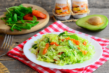 Raw сabbage avocado salad. Easy fresh cabbage salad with avocado, dried apricots, ruccola and sesame on a plate and on a wooden table. Raw vegan diet weight loss. Rustic style. Closeup