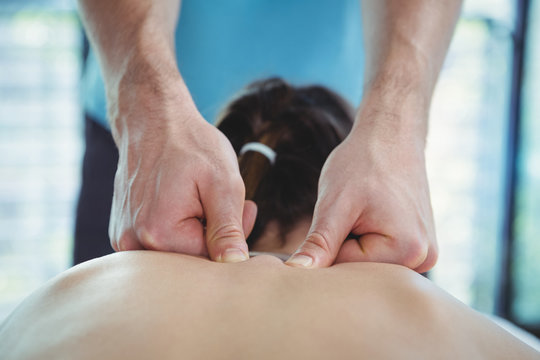 Physiotherapist giving physical therapy to the back of a female patient
