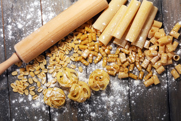Various mix of pasta on grey rustic background. Diet and food concept.