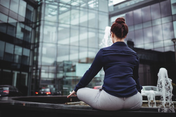 Rear view of businesswoman doing yoga