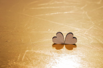 Fototapeta premium Two wooden hearts on golden background, concept for love, dating and romance with copy space