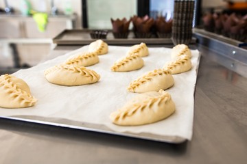 Raw pies stuffed lying in a tray on the table in the bakery