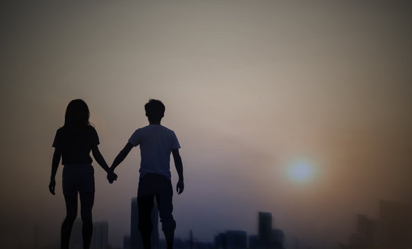 silhouette of a couple walking in a city at dawn or dusk with sky sunset.
