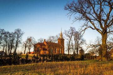 Zabytkowy kościół na wzgórzu oświetlony zachodzący słońcem w miejscowości Górka Pabianicka, Polska © Senatorek