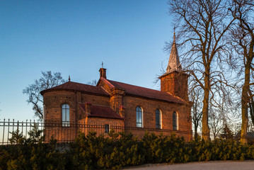 Zabytkowy kościół na wzgórzu oświetlony zachodzący słońcem w miejscowości Górka Pabianicka, Polska © Senatorek