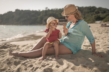 Mother with child on tropical beach ieating icecream