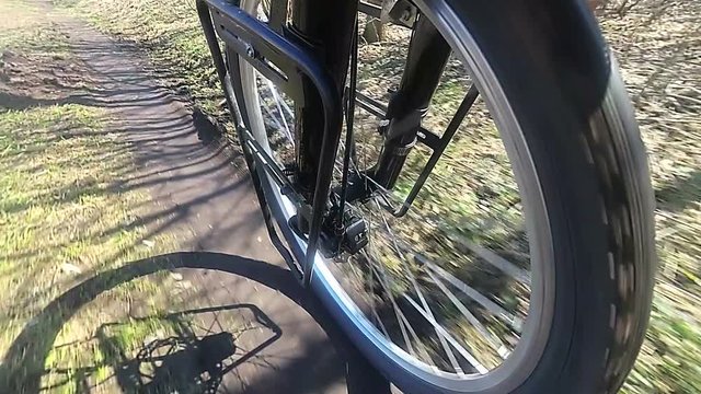 Wheel of  bicycle goes on  dirt road. Slow motion. Side view


