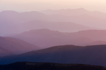 Obraz premium Picturesque summer landscape with colorful sunrise on Carpathian mountains. Mountain ranges in morning light. Travel background concept