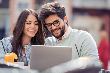 Happy couple at coffee shop using laptop