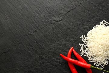 Jasmine rice and red chili peppers on slate board, copy space