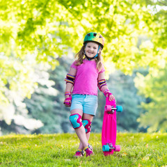 Child riding skateboard in summer park