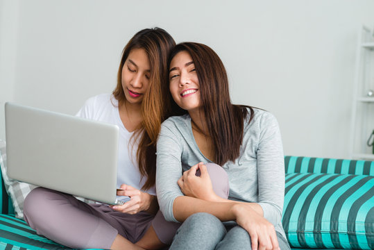 Beautiful young asian women LGBT lesbian happy couple sitting on sofa buying online using laptop in living room at home. LGBT lesbian couple together indoors concept. Spending nice time at home.