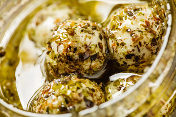 cheese chevre marinated in olive oil with herbs in glass jar