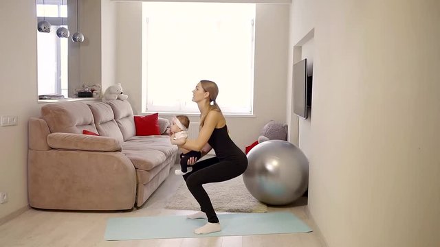 woman strengthens the buttocks muscles during the home exercise, she hold baby