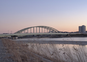 Fototapeta na wymiar 夕暮れの河川敷とアーチ橋