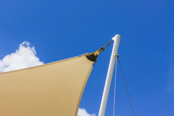 Construction details: Stainless steel support of roof canvas to white round steel post against the blue sky background