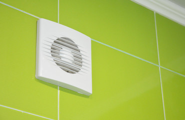 Bath vent fan with green tiles wall. White bathroom ventilation system.