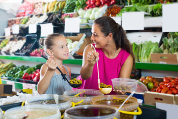 Smiling woman with daughter taking pickled olives