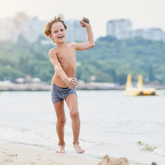Smiling young boy running along summer beach and having fun, image with square aspect ratio