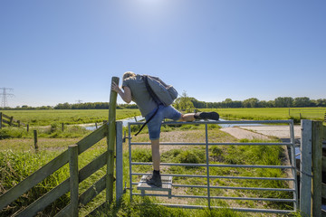 female hiker climbs over a fence with a special step for walkers