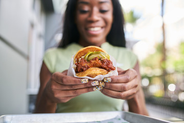 african american woman holding nashville hot chicken sandwich - Powered by Adobe